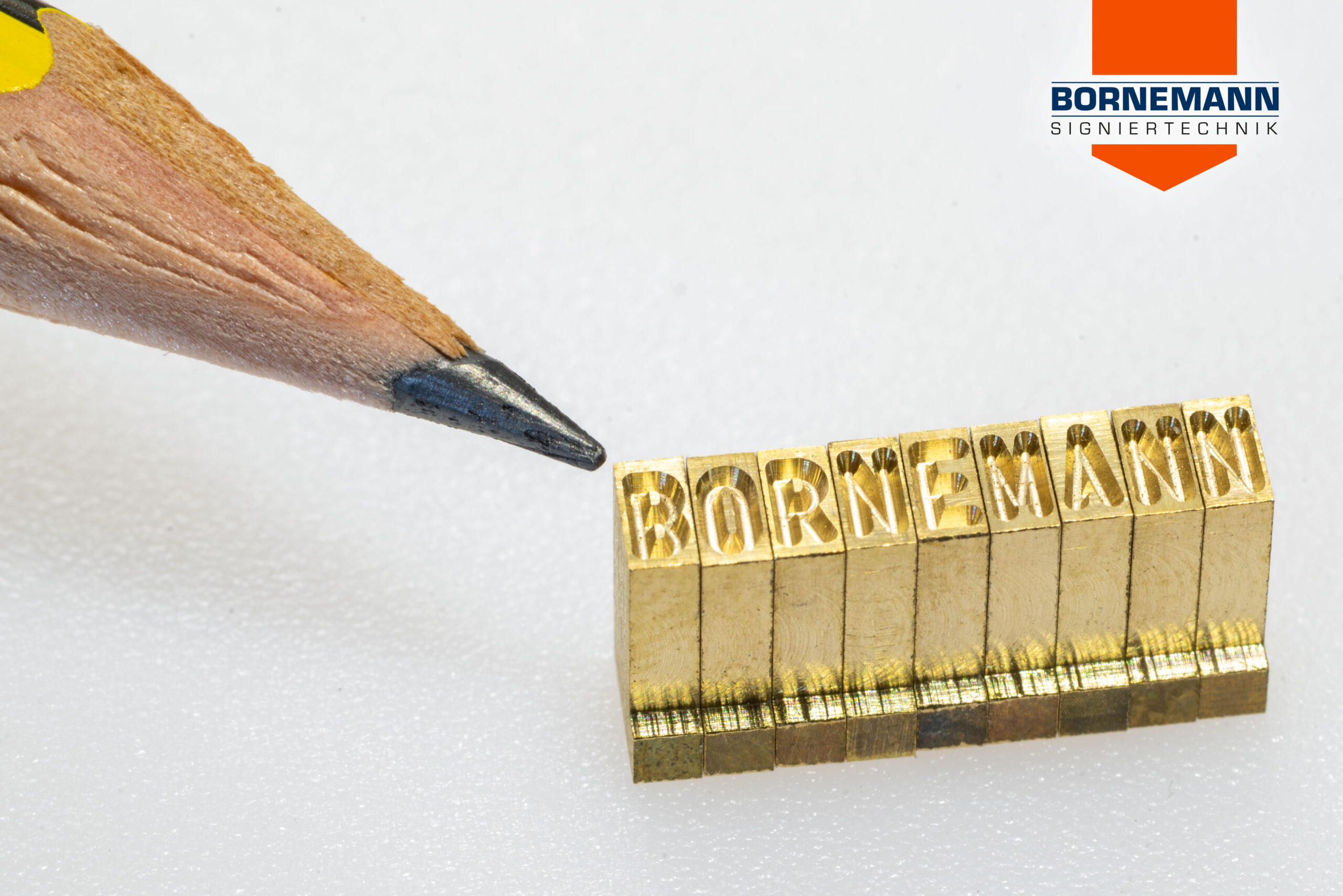 Mikrosatzzeichen formen den Schriftzug „BORNEMANN“, daneben eine Bleistiftspitze als Größenvergleich.